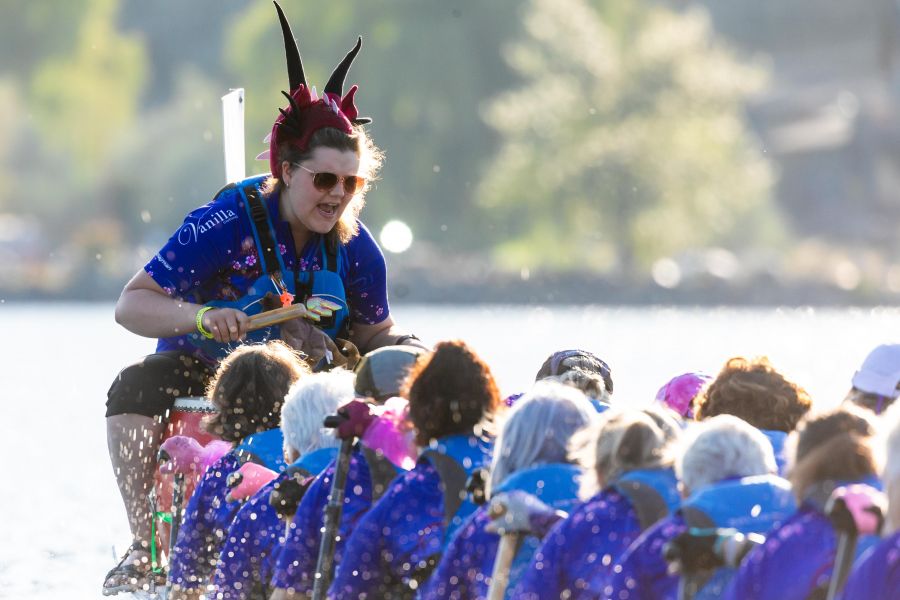 Team drummer with red pointy hat and the rest of the team paddling.